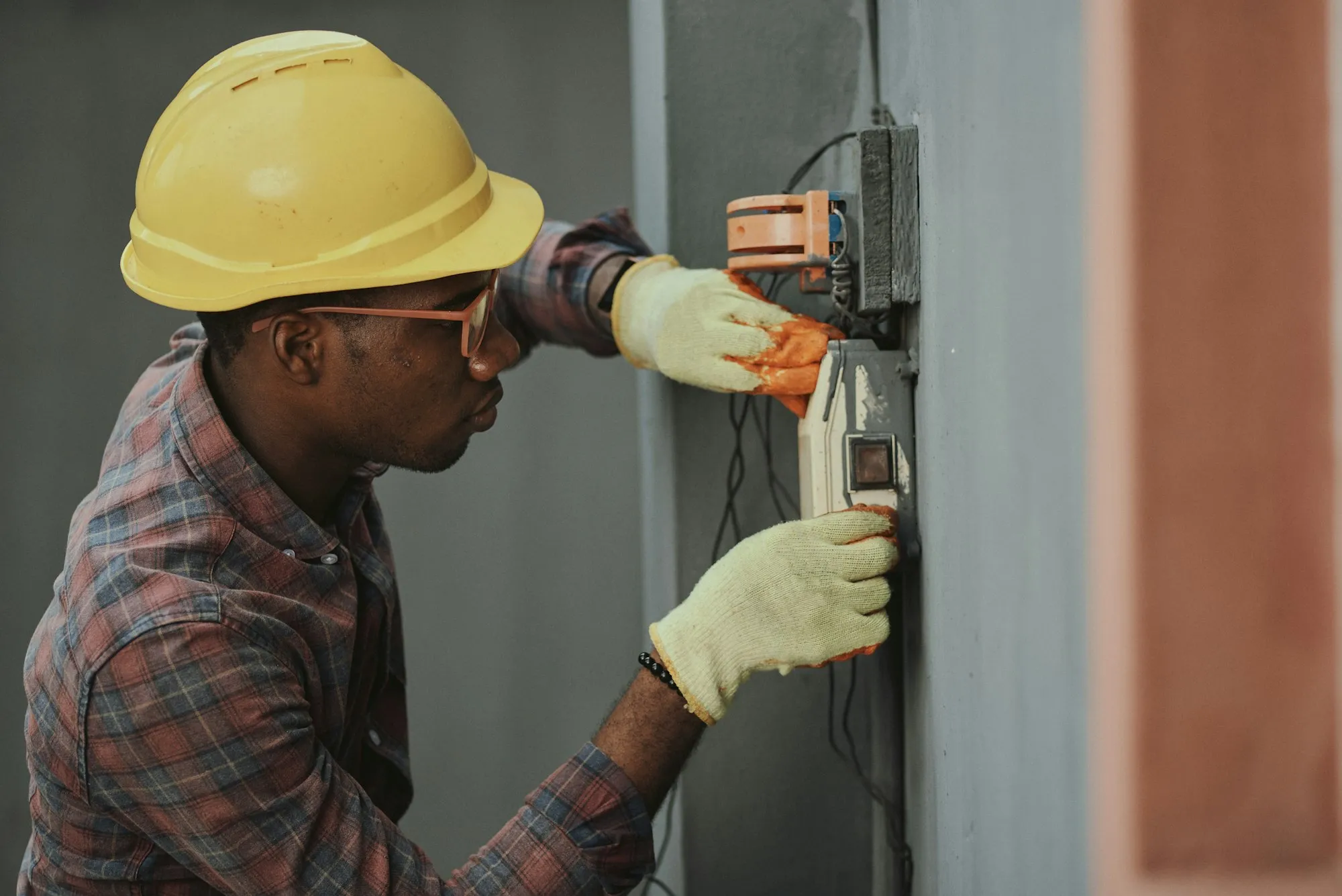 Électricien raccordant un boîtier électrique mural